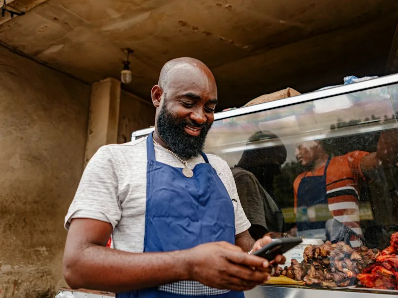 A food business owner in an apron at his counter.
